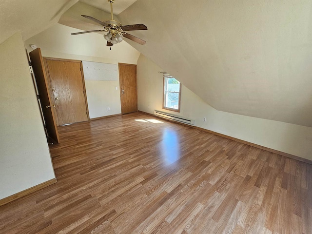 bonus room featuring light wood finished floors, a ceiling fan, vaulted ceiling, baseboards, and baseboard heating