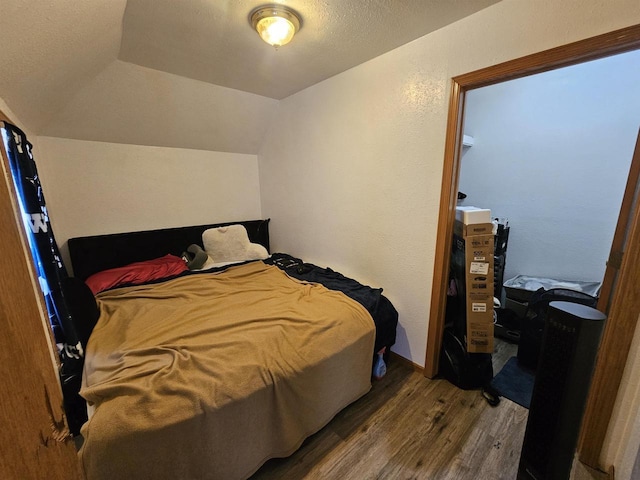 bedroom with lofted ceiling and wood finished floors