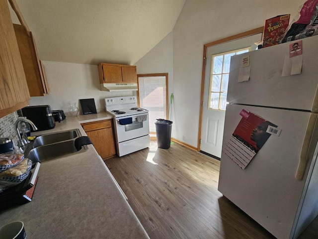 kitchen featuring wood finished floors, white appliances, under cabinet range hood, vaulted ceiling, and a sink