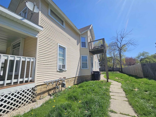 view of home's exterior featuring fence, a yard, a balcony, and central air condition unit