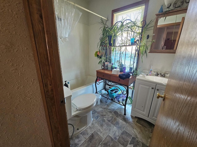 full bathroom with stone finish flooring, vanity, toilet, and shower / bath combo with shower curtain