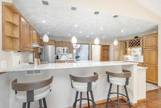 kitchen featuring light stone countertops, open shelves, a peninsula, stainless steel appliances, and under cabinet range hood