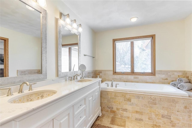 bathroom featuring double vanity, a garden tub, and a sink