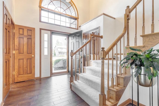 entrance foyer with stairs, a high ceiling, baseboards, and wood finished floors