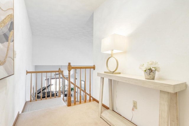 hall featuring an upstairs landing, baseboards, and carpet floors