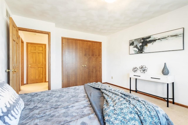 carpeted bedroom with a closet and baseboards