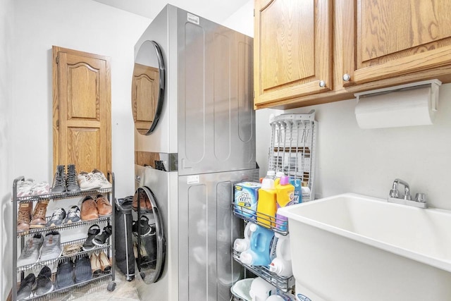 laundry room with a sink, cabinet space, and stacked washer / dryer