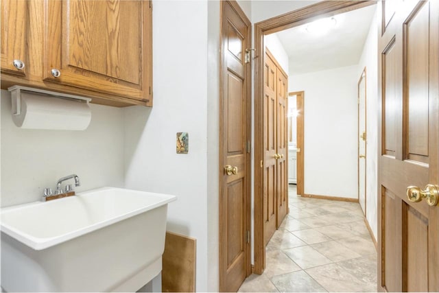 laundry room with a sink and baseboards