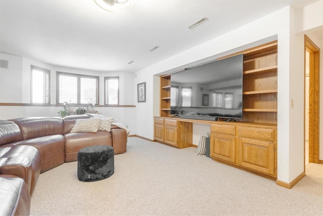 living area with visible vents, built in shelves, baseboards, light carpet, and built in study area