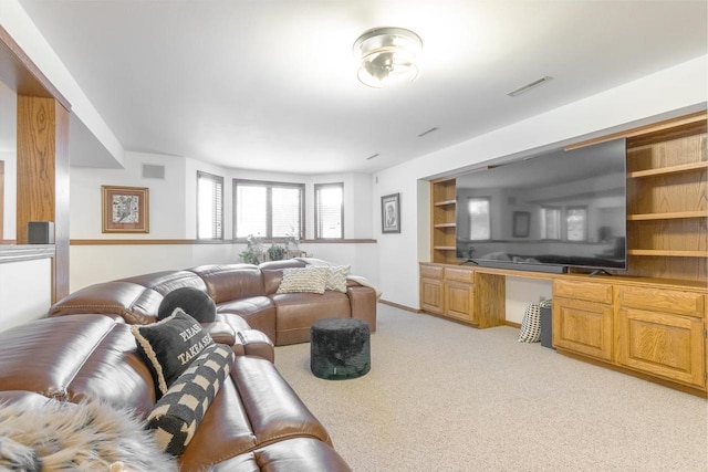 living room with built in features, visible vents, light carpet, and built in study area