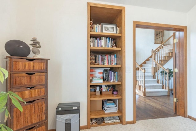 hallway featuring carpet flooring, stairs, and baseboards