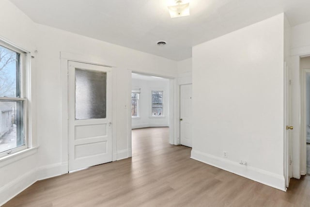 spare room with visible vents, baseboards, and light wood finished floors