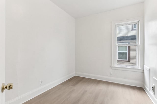 spare room with baseboards and light wood-style floors