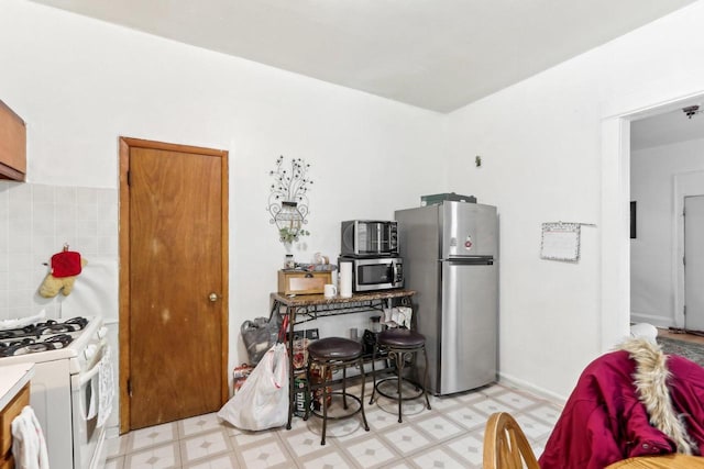 kitchen with tasteful backsplash, light floors, appliances with stainless steel finishes, and light countertops