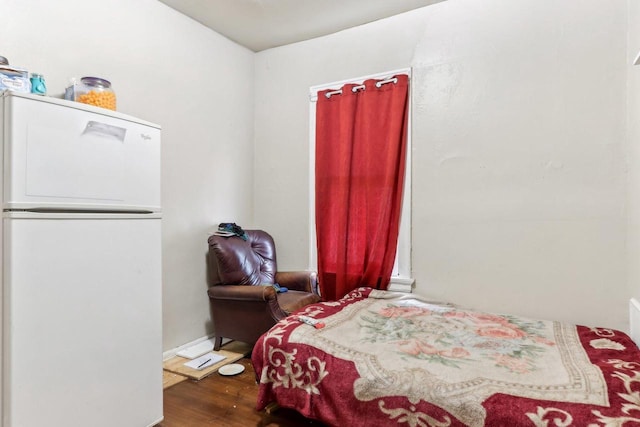 bedroom with wood finished floors and freestanding refrigerator