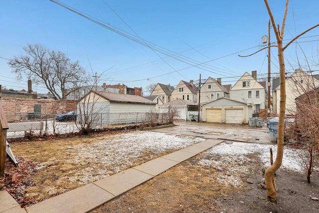 view of yard with a residential view, a detached garage, an outdoor structure, and fence