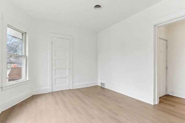 empty room featuring light wood-type flooring, baseboards, and visible vents