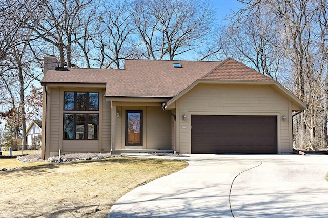 view of front of home featuring driveway, a front yard, a shingled roof, a garage, and a chimney