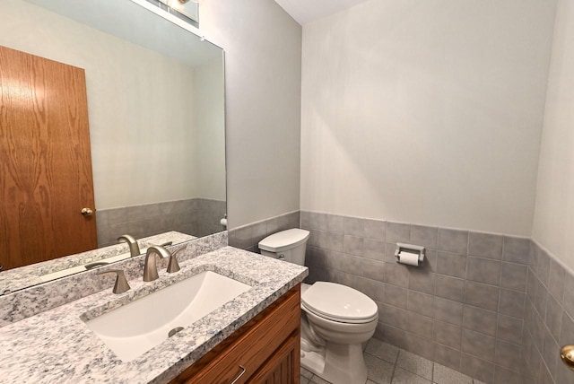 bathroom featuring tile walls, a wainscoted wall, toilet, tile patterned floors, and vanity