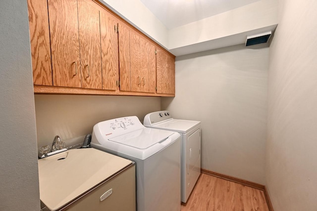 washroom with baseboards, washing machine and dryer, light wood-type flooring, cabinet space, and a sink