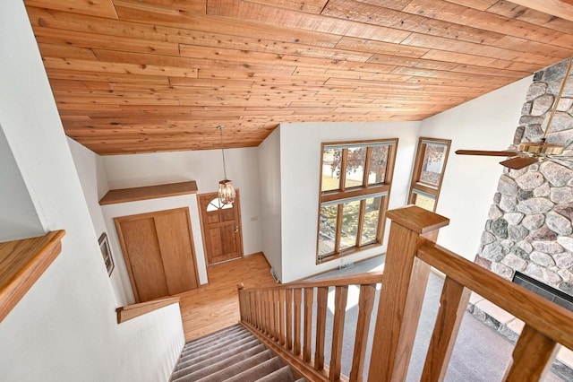 stairs featuring wood finished floors, a fireplace, wood ceiling, and vaulted ceiling