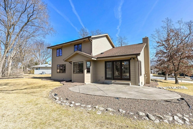 back of house featuring a patio area, roof with shingles, and a chimney