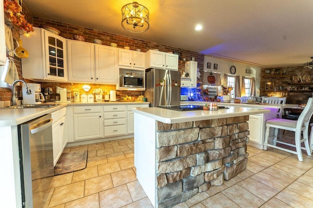 kitchen with appliances with stainless steel finishes, brick wall, light countertops, and a sink