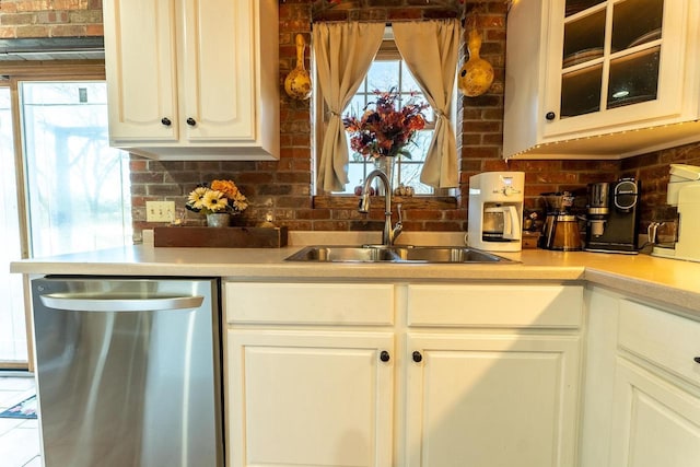 kitchen featuring a sink, glass insert cabinets, stainless steel dishwasher, and light countertops