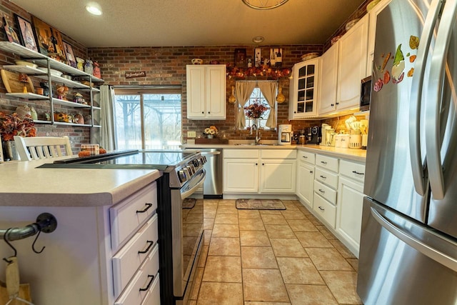 kitchen featuring a sink, a wealth of natural light, brick wall, and stainless steel appliances