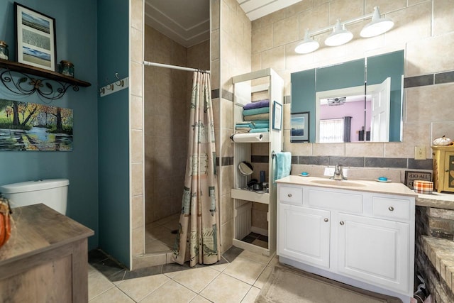 bathroom featuring tasteful backsplash, tile patterned flooring, vanity, a stall shower, and tile walls