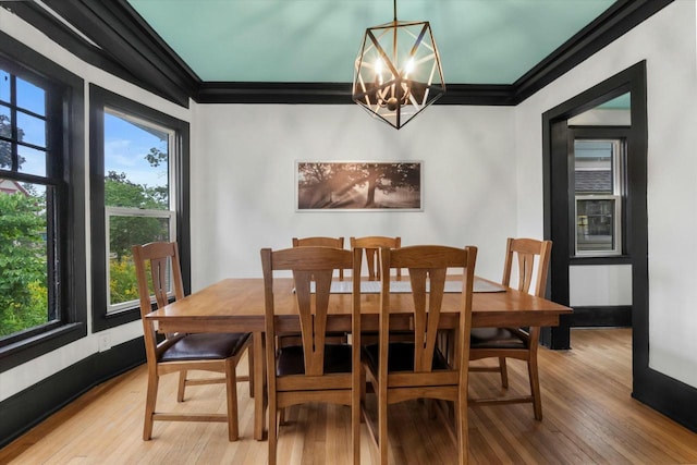 dining room featuring light wood-type flooring, a chandelier, baseboards, and ornamental molding