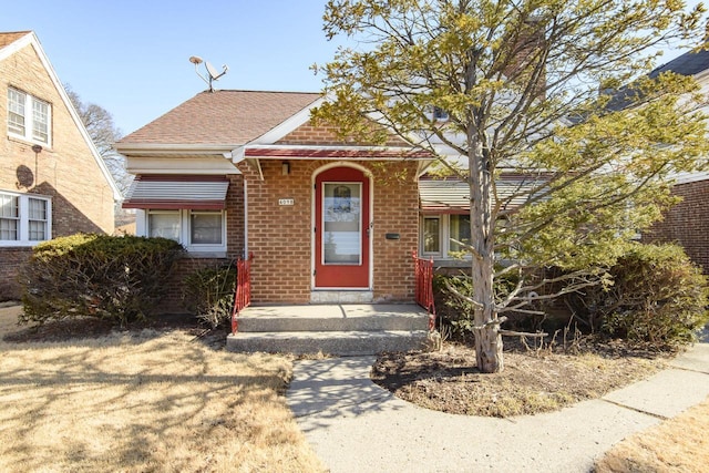 bungalow-style home featuring brick siding and a shingled roof