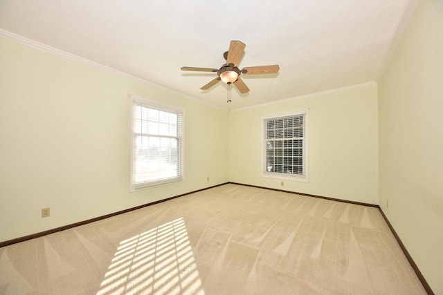 carpeted empty room featuring ceiling fan, crown molding, and baseboards