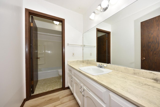 bathroom with shower / washtub combination, toilet, vanity, and wood finished floors