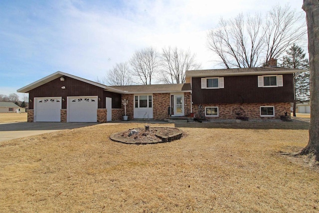 split level home featuring a front lawn, concrete driveway, an attached garage, brick siding, and a chimney