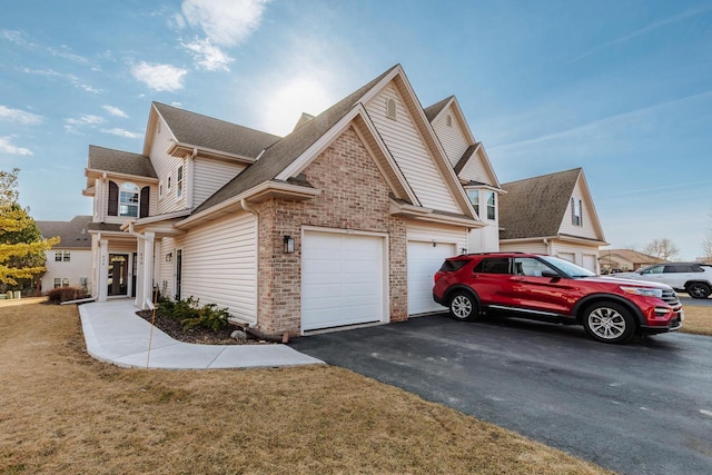 view of side of property featuring brick siding, an attached garage, roof with shingles, a lawn, and driveway