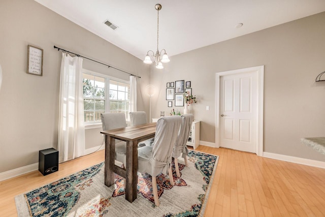 dining area featuring an inviting chandelier, light wood-style floors, visible vents, and baseboards