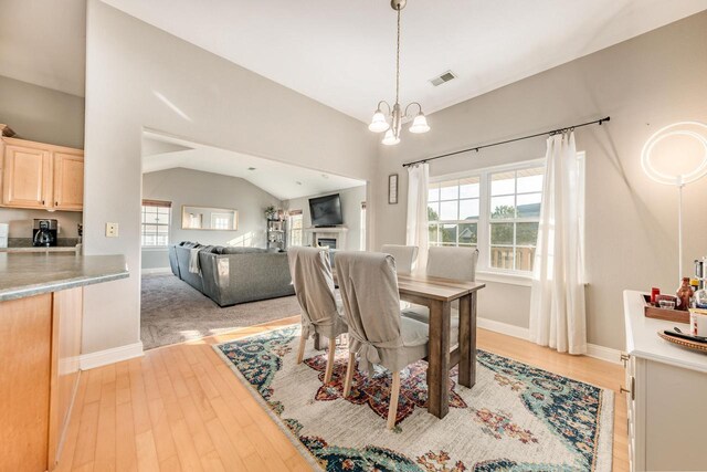 dining space with visible vents, lofted ceiling, a notable chandelier, and a healthy amount of sunlight