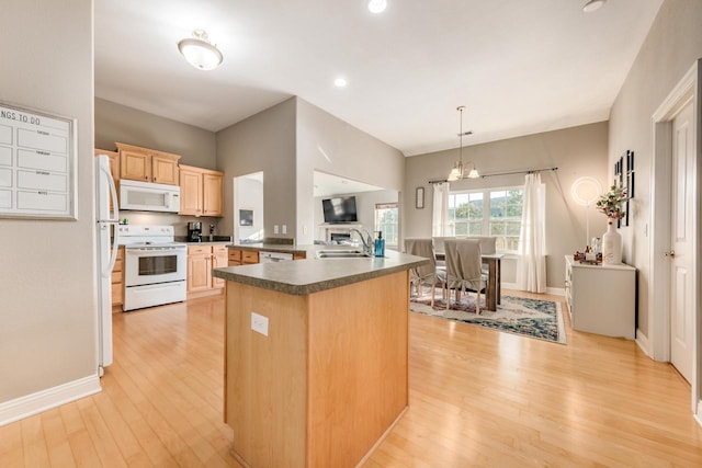 kitchen with white appliances, light brown cabinets, a sink, dark countertops, and light wood-type flooring