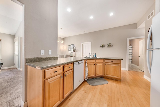 kitchen featuring visible vents, light wood-type flooring, a peninsula, white appliances, and a sink