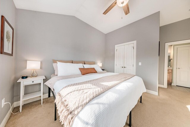 bedroom with a ceiling fan, baseboards, vaulted ceiling, a closet, and light carpet