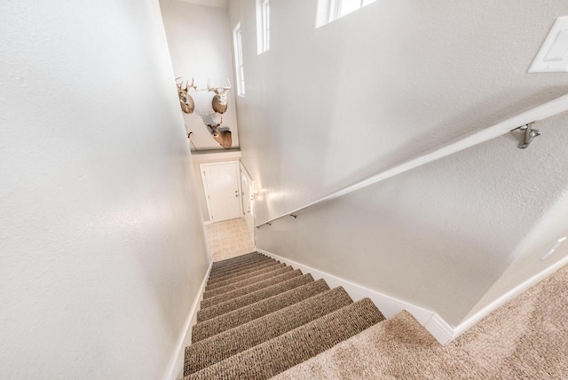 stairs with a high ceiling, baseboards, and carpet floors