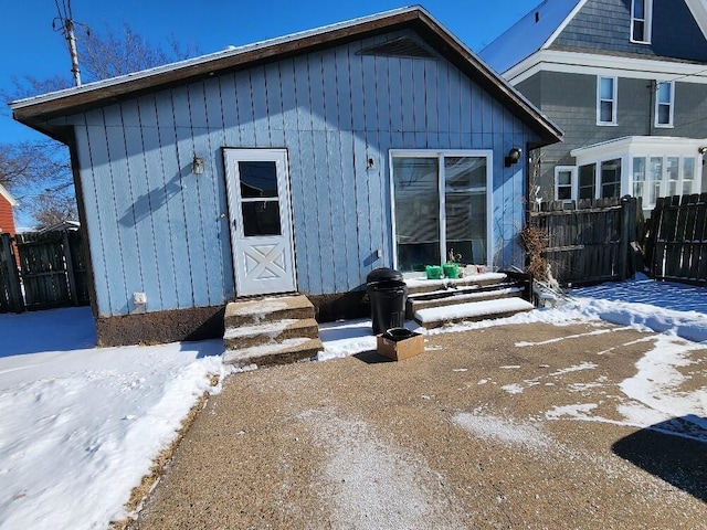 snow covered back of property with entry steps and fence