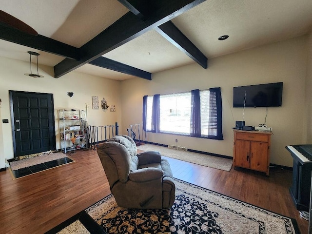 living room featuring beamed ceiling, baseboards, visible vents, and wood finished floors