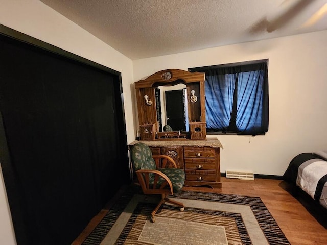 bedroom with visible vents, baseboards, dark wood-type flooring, and a textured ceiling