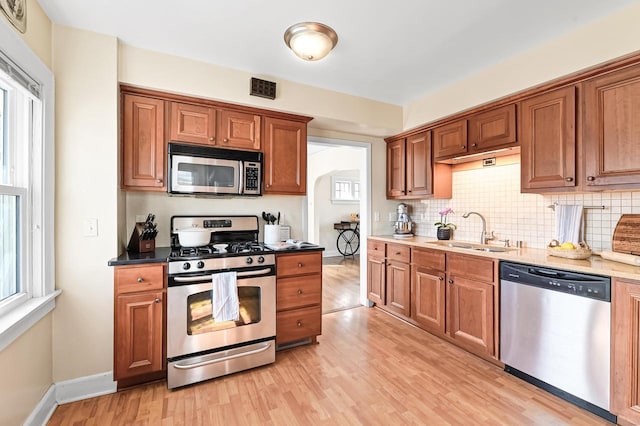 kitchen featuring plenty of natural light, light wood-type flooring, appliances with stainless steel finishes, and a sink