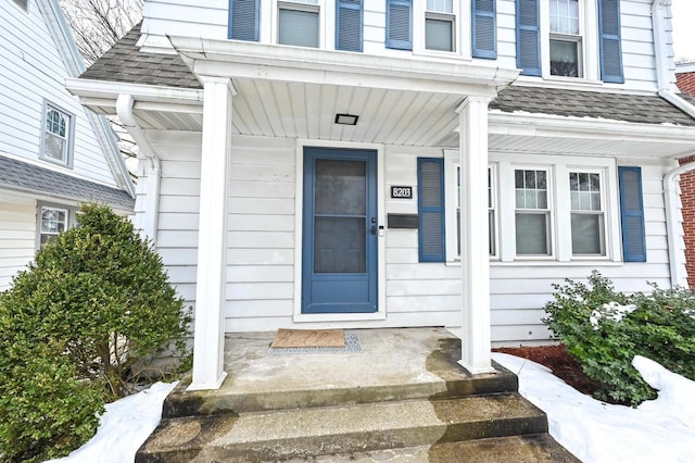 entrance to property featuring roof with shingles