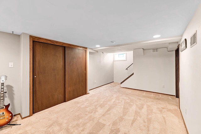 basement featuring light carpet, visible vents, stairway, and baseboards