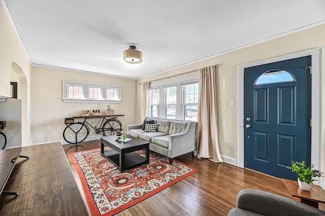 living room featuring crown molding, wood finished floors, arched walkways, and baseboards