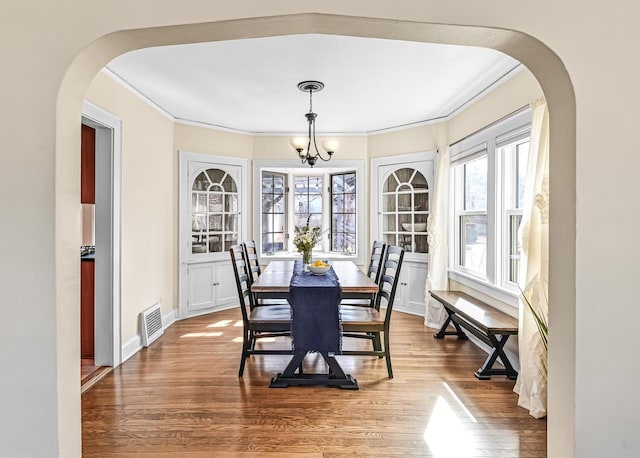 dining space featuring plenty of natural light, arched walkways, and wood finished floors